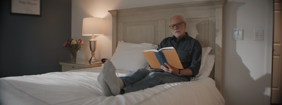 Äldre man läser en bok i sängen i varmt kvällsljus