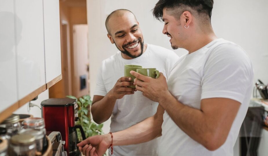 Två män pratar över kaffe i köket inför hemmets veckoplanering